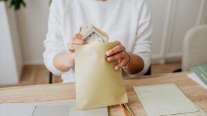 an individual putting cash into an envelope for savings as part of a budget