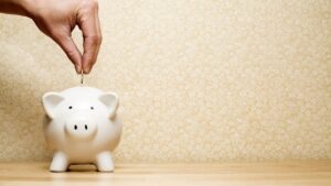 a hand placing money into a piggy bank to start savings