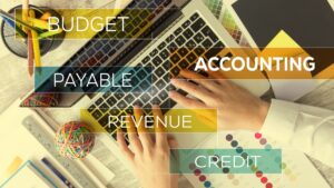 Hands on laptop with fintech-related terms like budget, accounting, and revenue