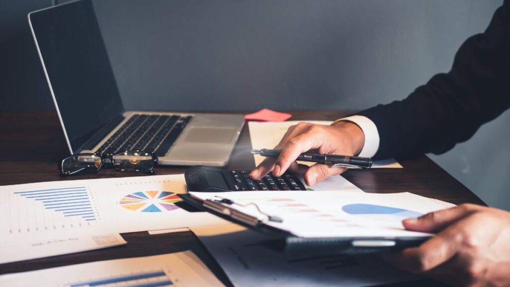 Small business owner reviewing mid-year financials and creating a business budget on a laptop